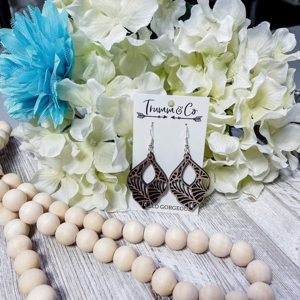 Bright photo with white and turquoise flower, wooden beads showing off Walnut Wood laser cut boho dangle earrings from trumm and co.com