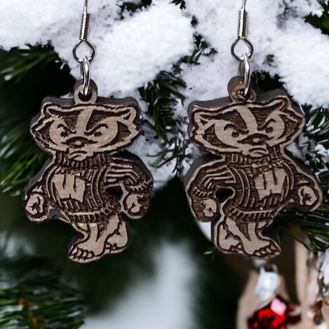 Bucky Badger wood dangle earrings, hanging off a snowy pine tree