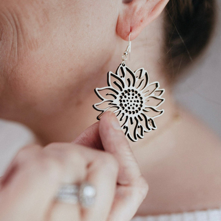 Lightweight Earrings|Laser cut, birch Sunflowers, woman holding onto the earring