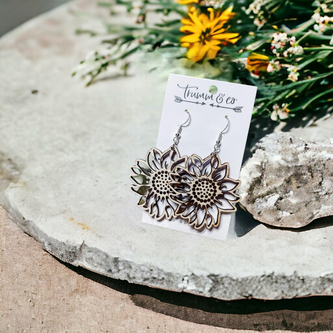 Lightweight Sunflower Earrings on a Trumm & Co earring card leaning on a rock and some wild flowers