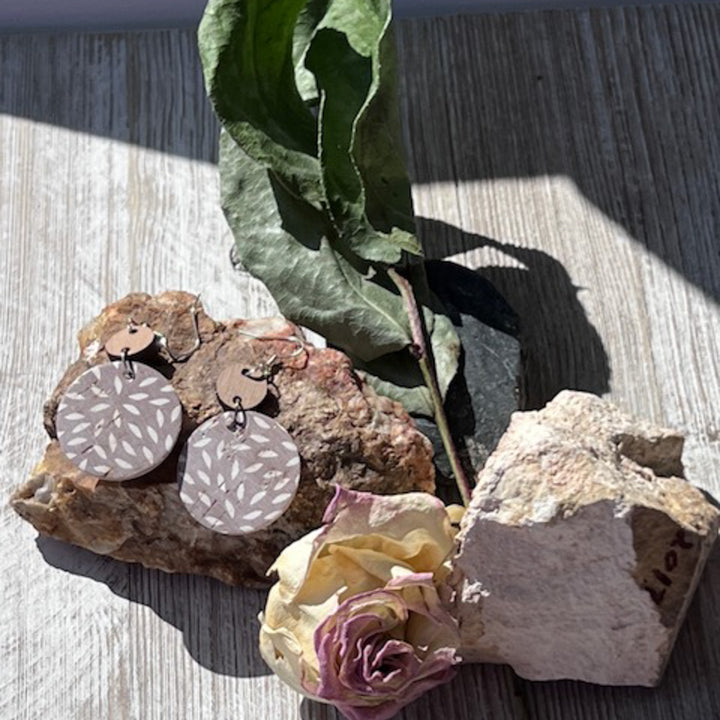 Outside photo with dangle earrings on a rock and a rose