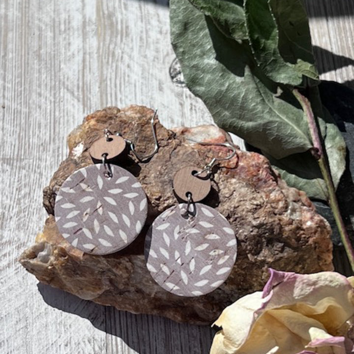 close up photo ashy taupe earrings on a rock