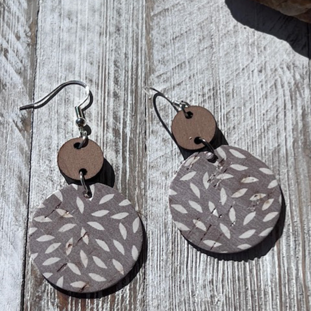 ashy taupe dangle earrings laying on a piece of wood