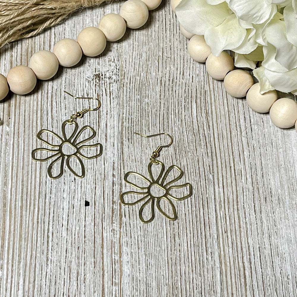 Raw brass flower earrings laying on white wash board made by Trumm & Co.