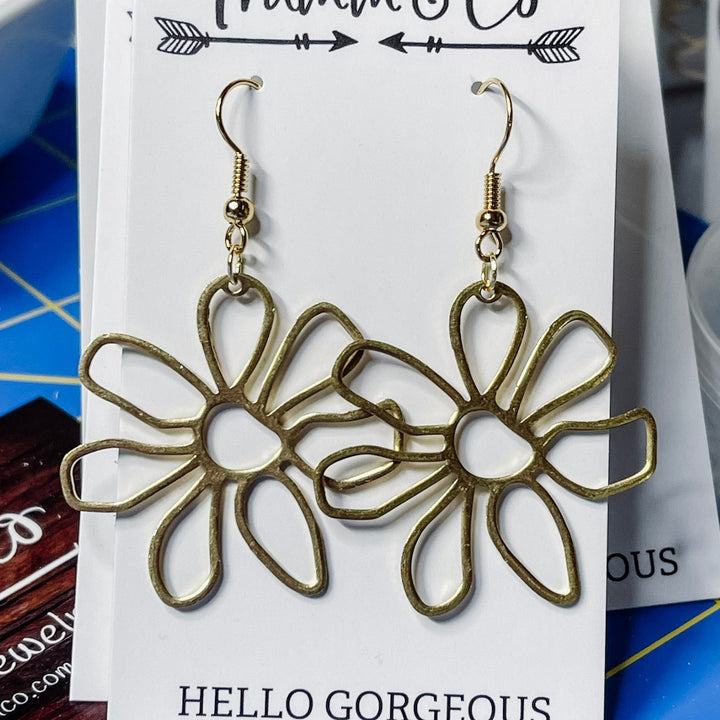 Close up photo of raw brass flower earrings on Trumm & Co white earring card