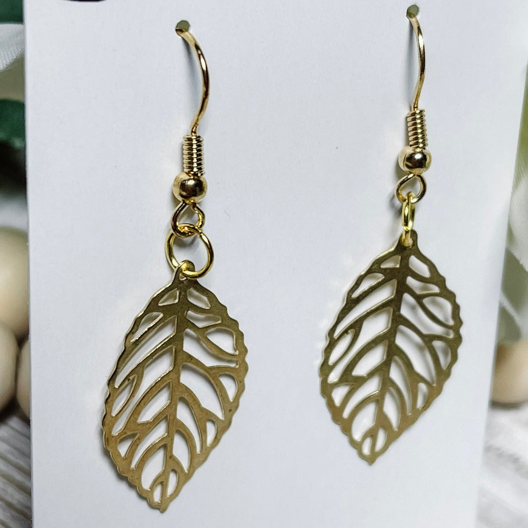 Side view close up intricate gold leaf dangle earrings.