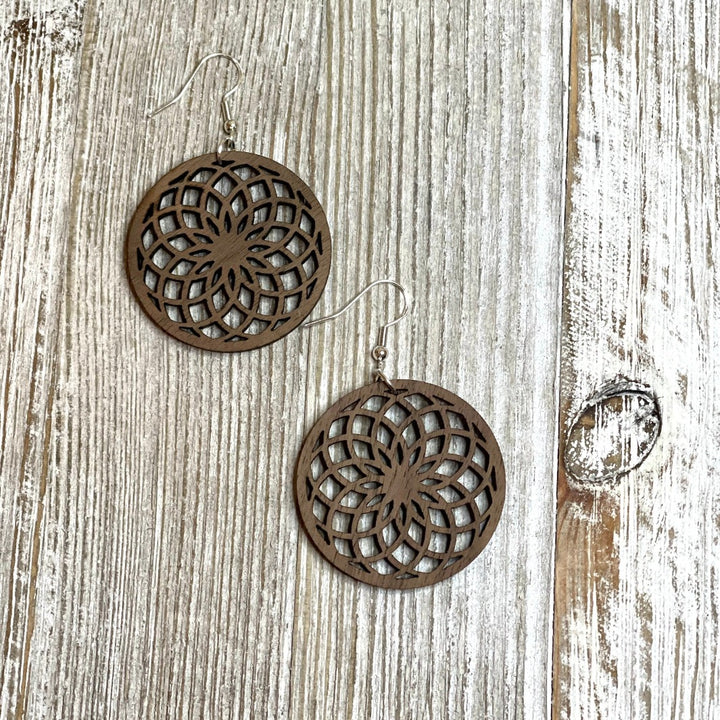 Wooden laser cut spiral flower earrings in walnut on whitewash board