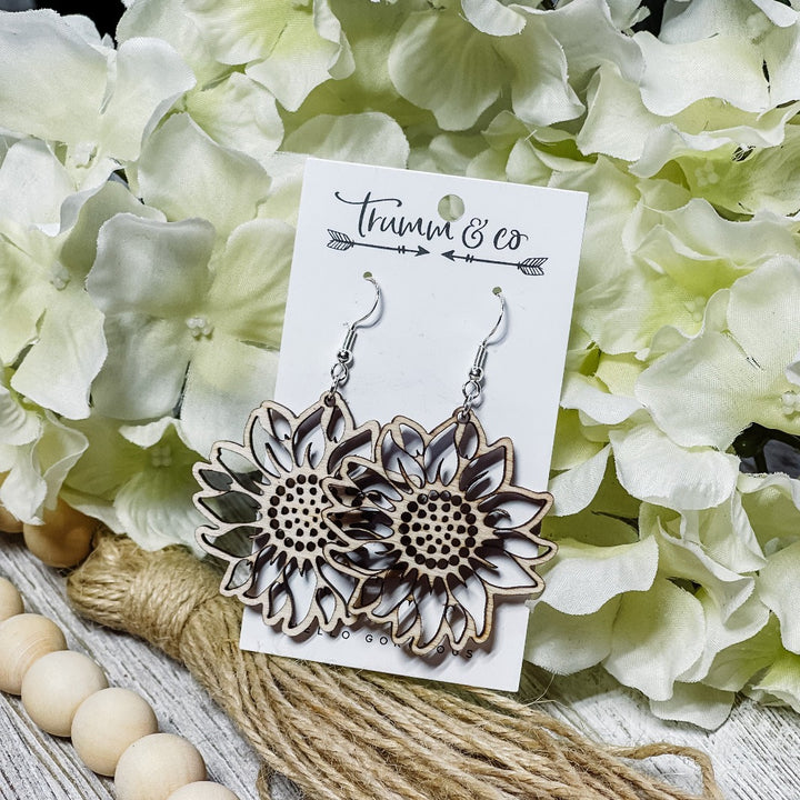 Wood sunflower earrings leaning against hydrangea flower on Trumm & Co earring card