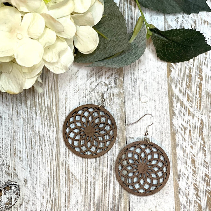 Spiral wooden flower earrings made with walnut on whitewash board with flower